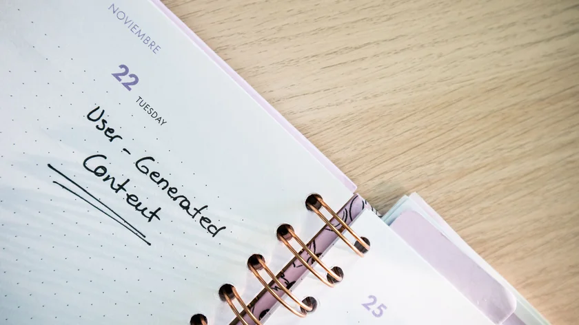 Un agenda ouvert présente une date et des notes manuscrites sur un bureau en bois.