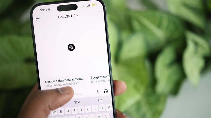 Une main tient un smartphone affichant ChatGPT devant des feuilles vertes.
