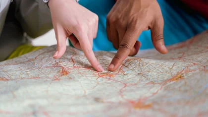 Deux mains montrent un emplacement sur une carte en papier.