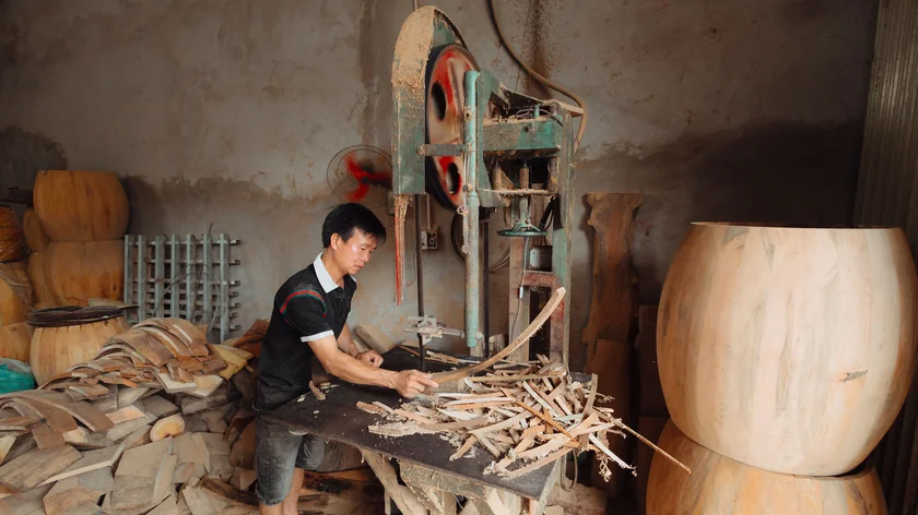 Un menuisier travaille une pièce de bois dans son atelier.