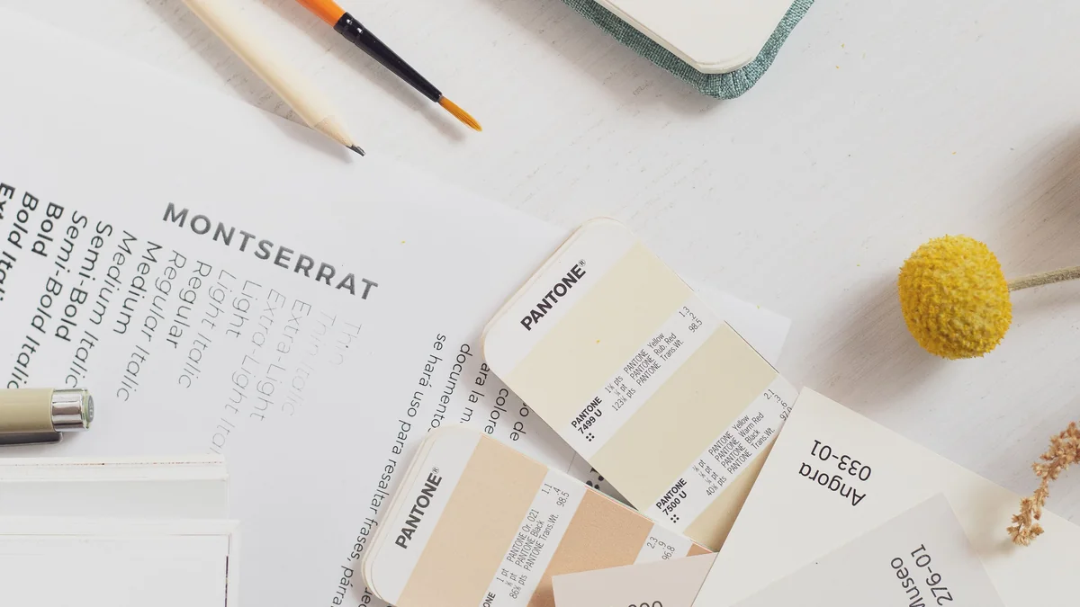 Un nuancier de couleurs et une feuille présentant différentes graisses de caractères sont disposés sur un bureau clair.