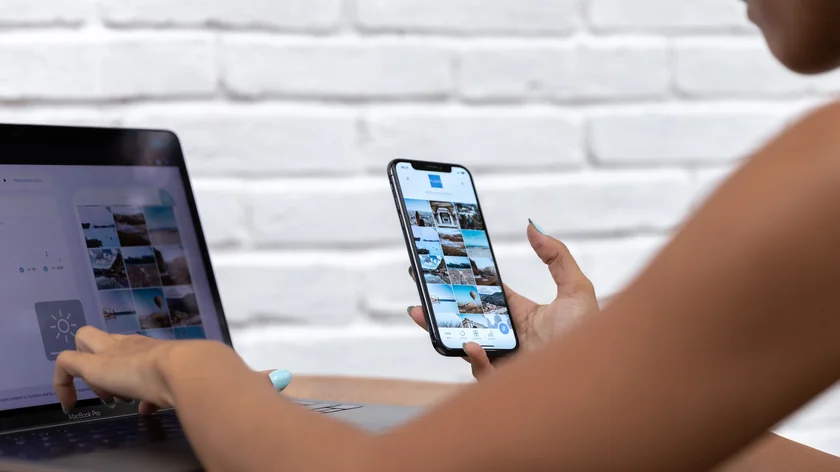 Une personne utilise un ordinateur portable et un smartphone pour préparer des publications.