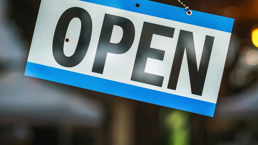Une pancarte ouvert est suspendue à la porte vitrée d'un commerce.