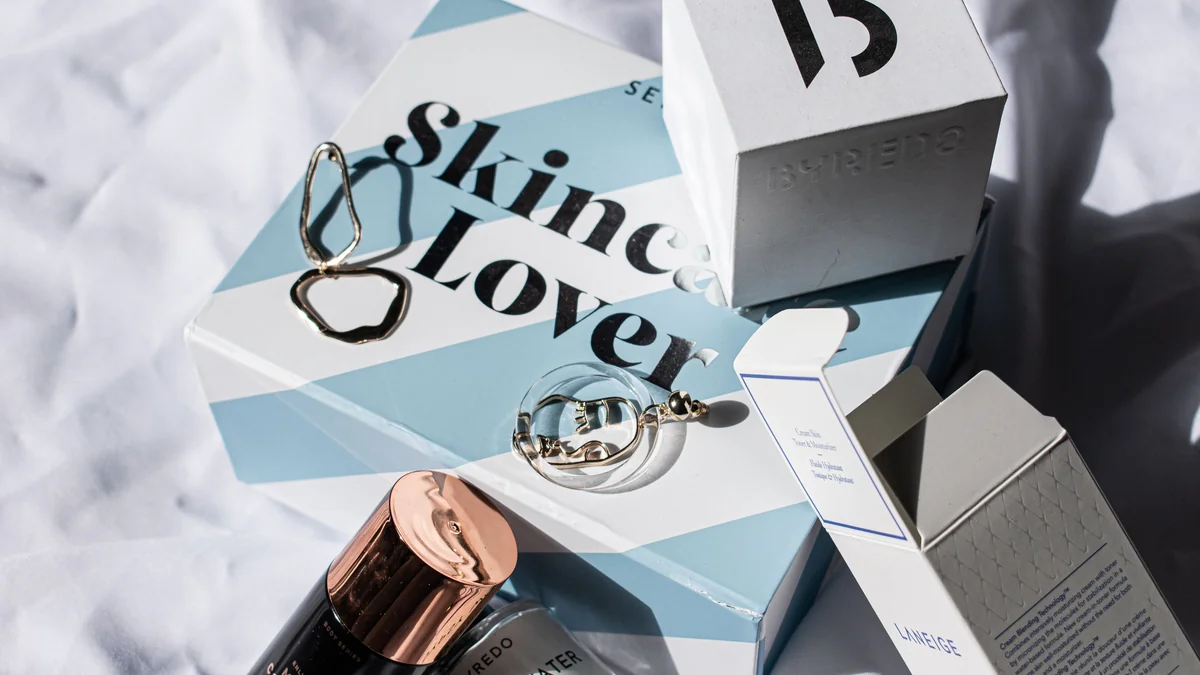 Flacons de parfum, boîtes et accessoires disposés sur un livre et un tissu clair.